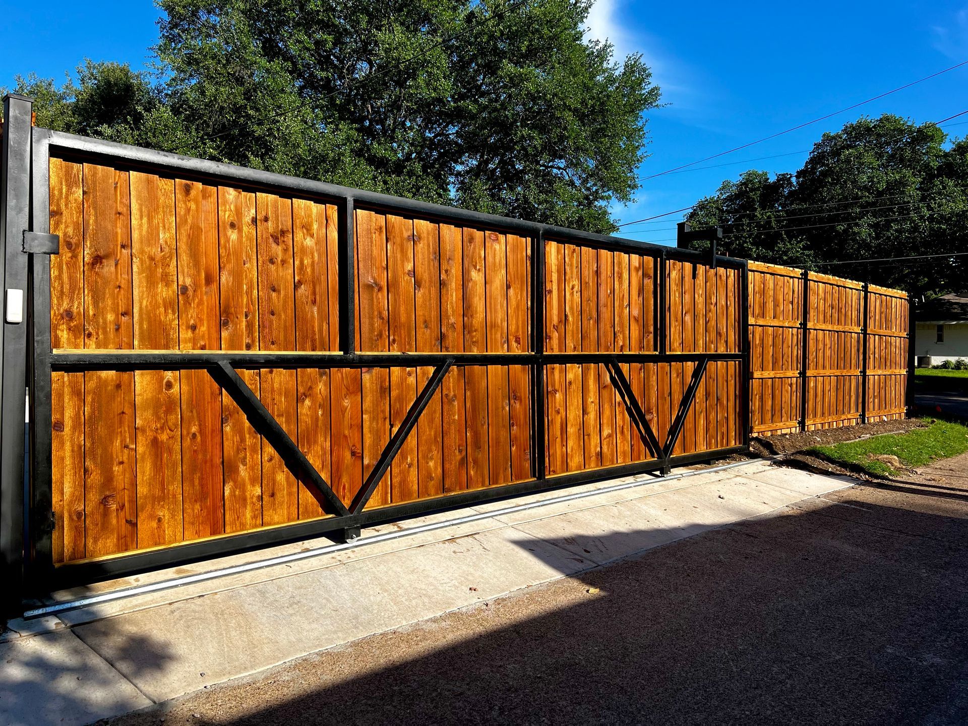 A wooden fence with a black frame is sitting on top of a concrete driveway.