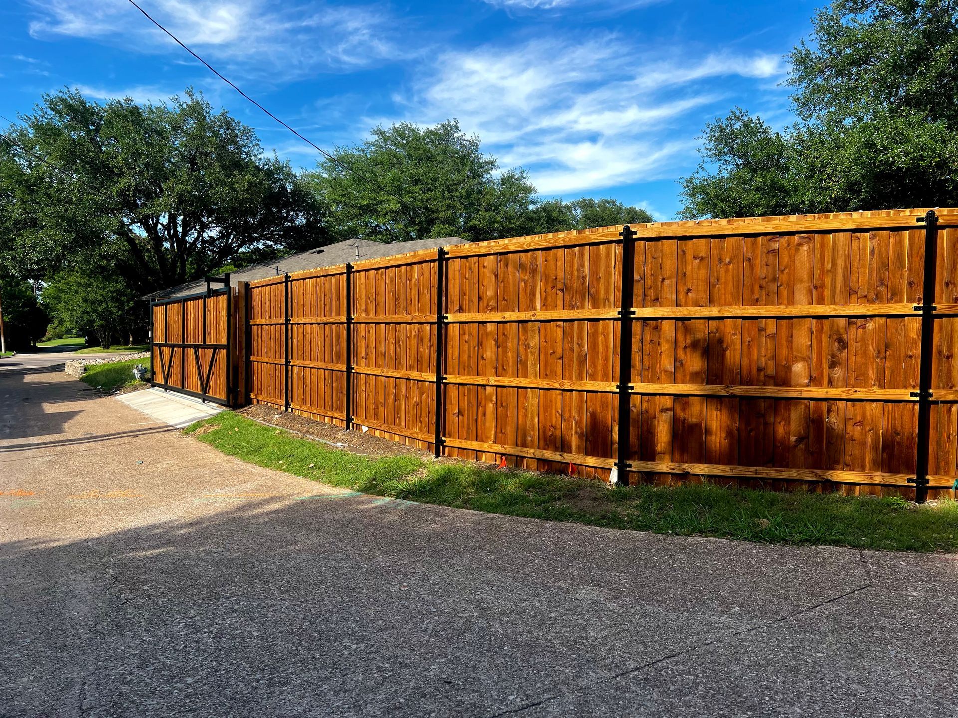 A wooden fence is along the side of a road.