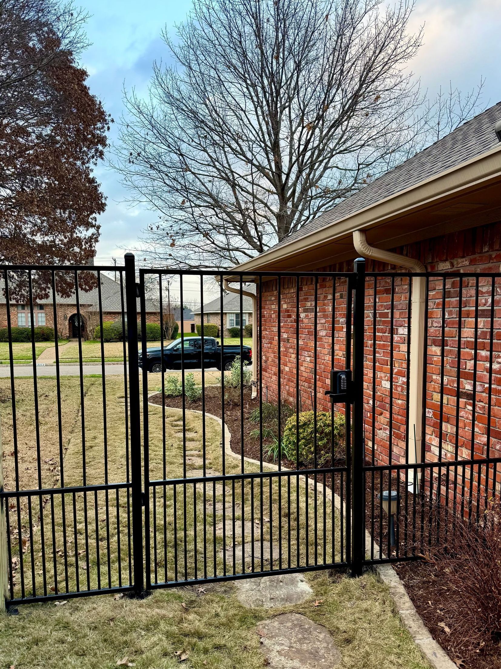A black wrought iron gate is in front of a brick building.