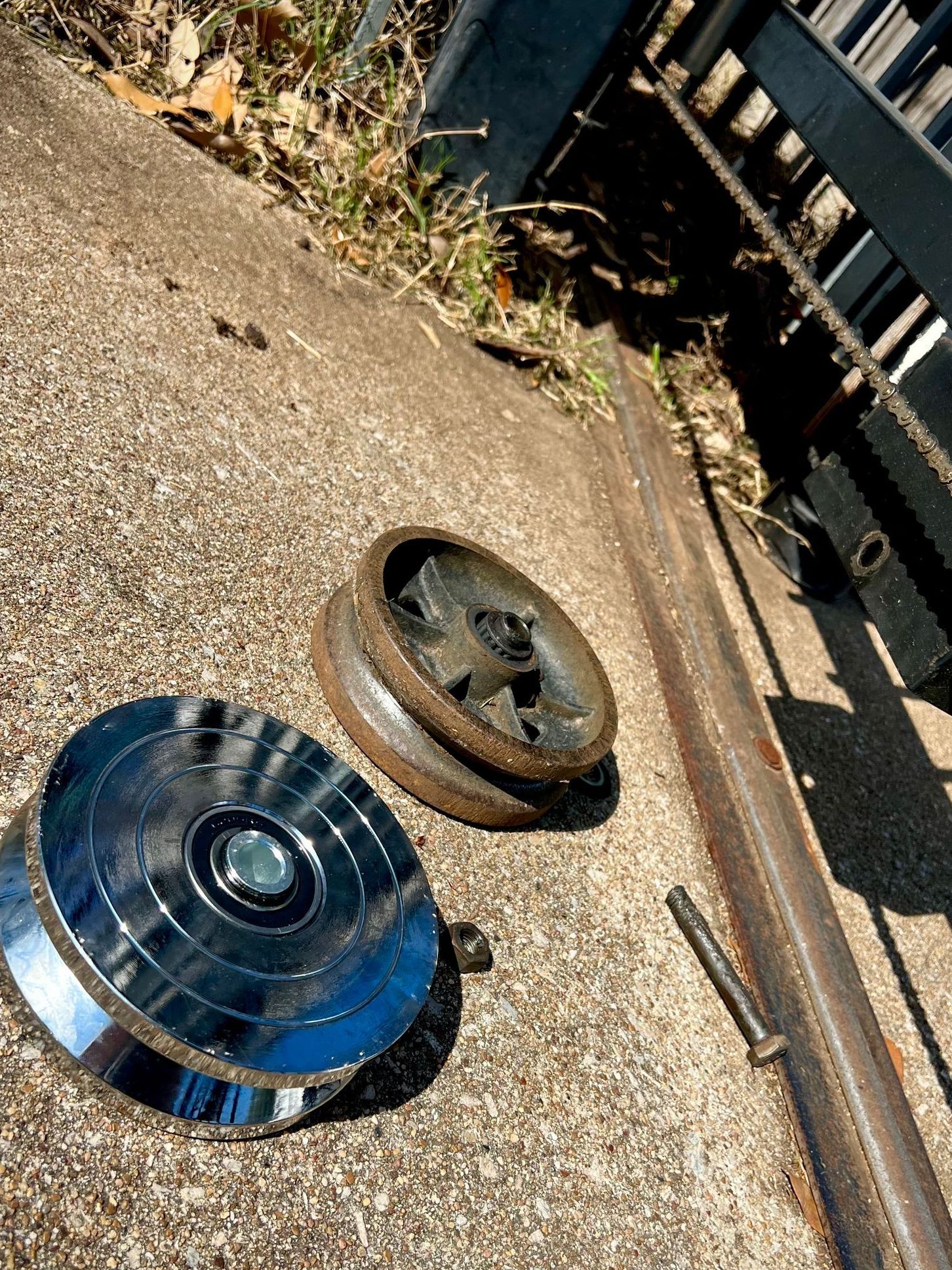 A metal object is laying on the ground next to a fence.
