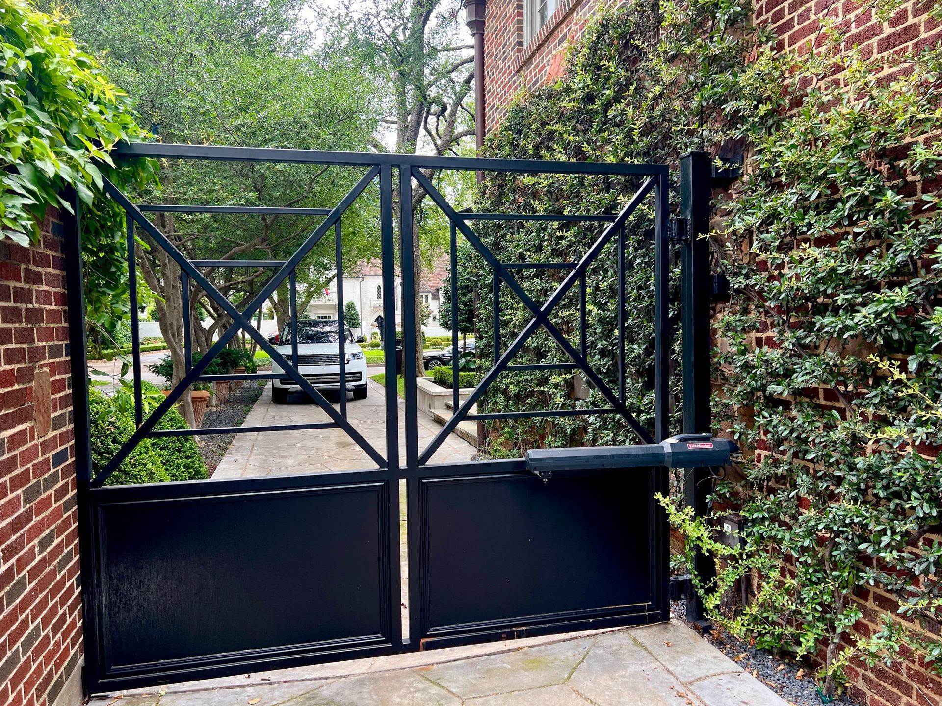 A black metal gate is sitting next to a brick wall.
