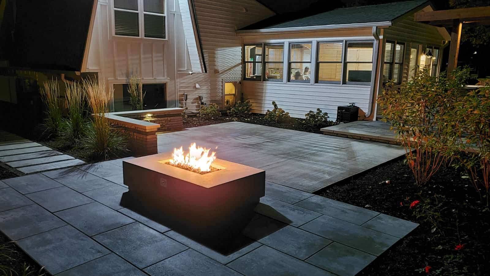 Fire pit on a patio at night, with a house in the background.