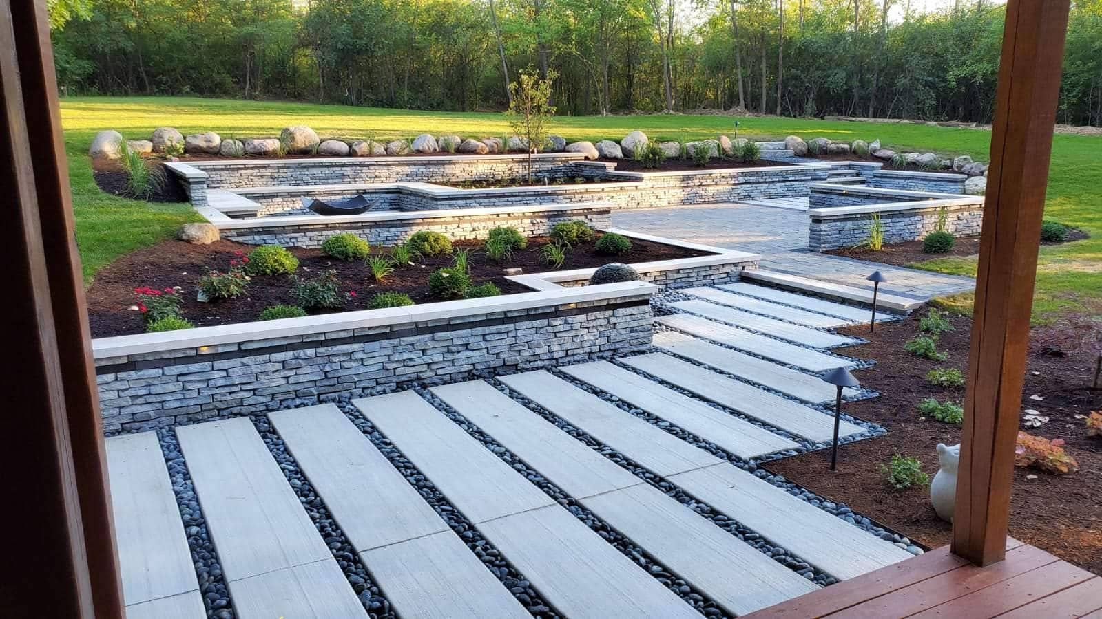 Stone patio with stairs, stone retaining walls, and tiered garden beds.