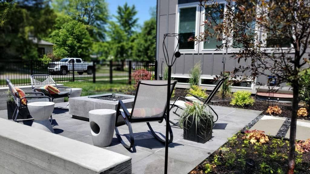 Outdoor patio with seating around a fire pit; modern home in the background.