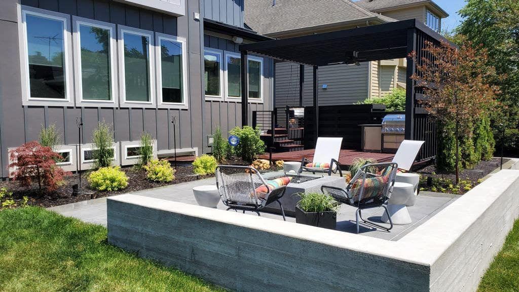 Backyard patio with fire pit and lounge area. Gray and white color scheme.