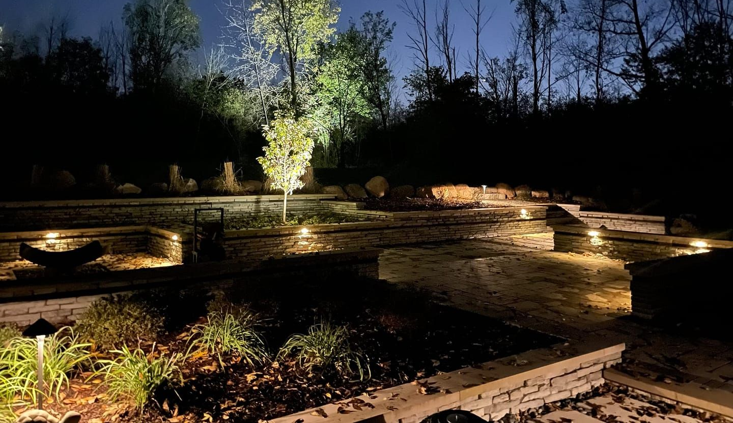 Nighttime garden with trees and path illuminated by landscape lighting.