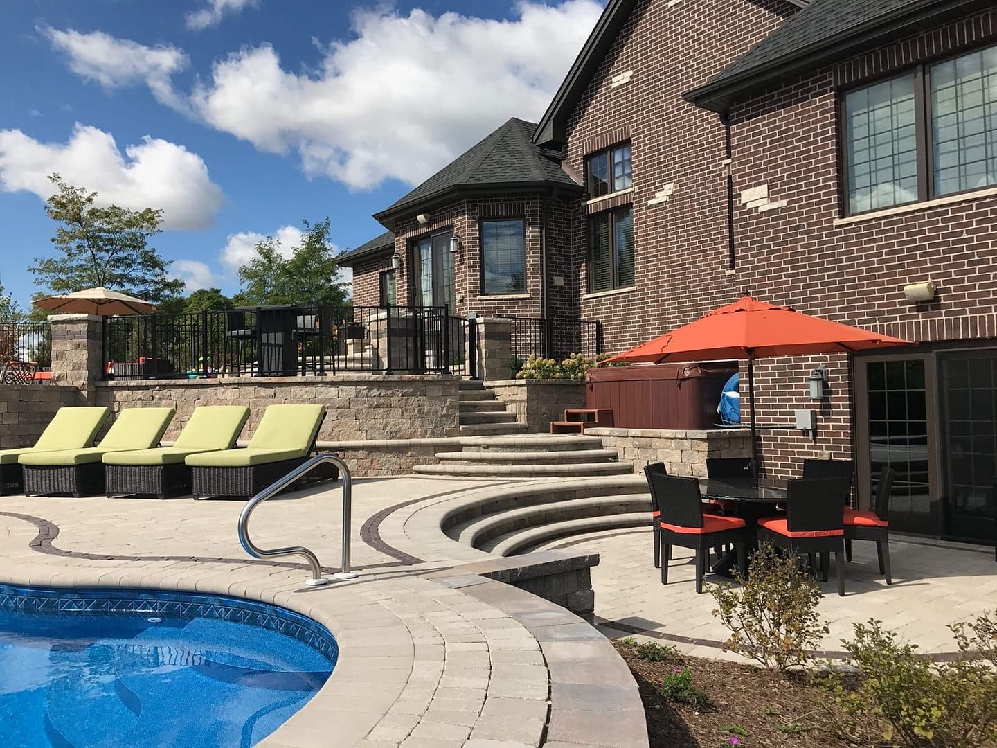 Backyard with pool, brick house, patio furniture, lounge chairs, and steps.