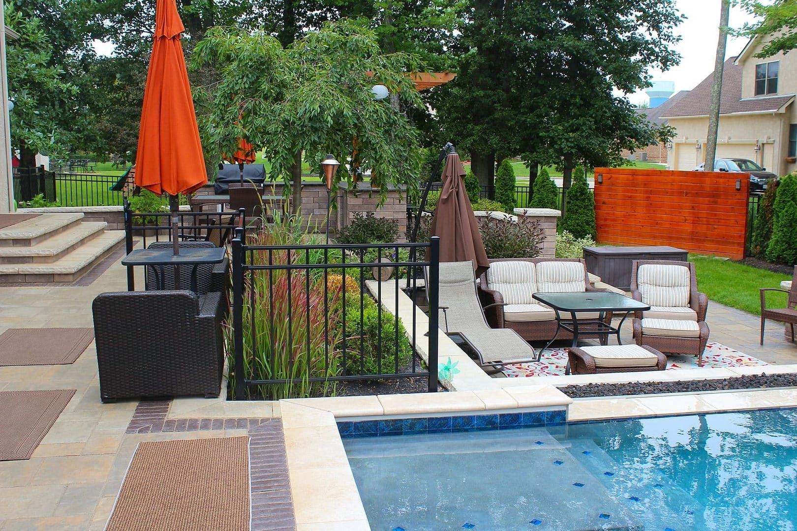 Backyard patio with pool, seating areas, and orange umbrella.