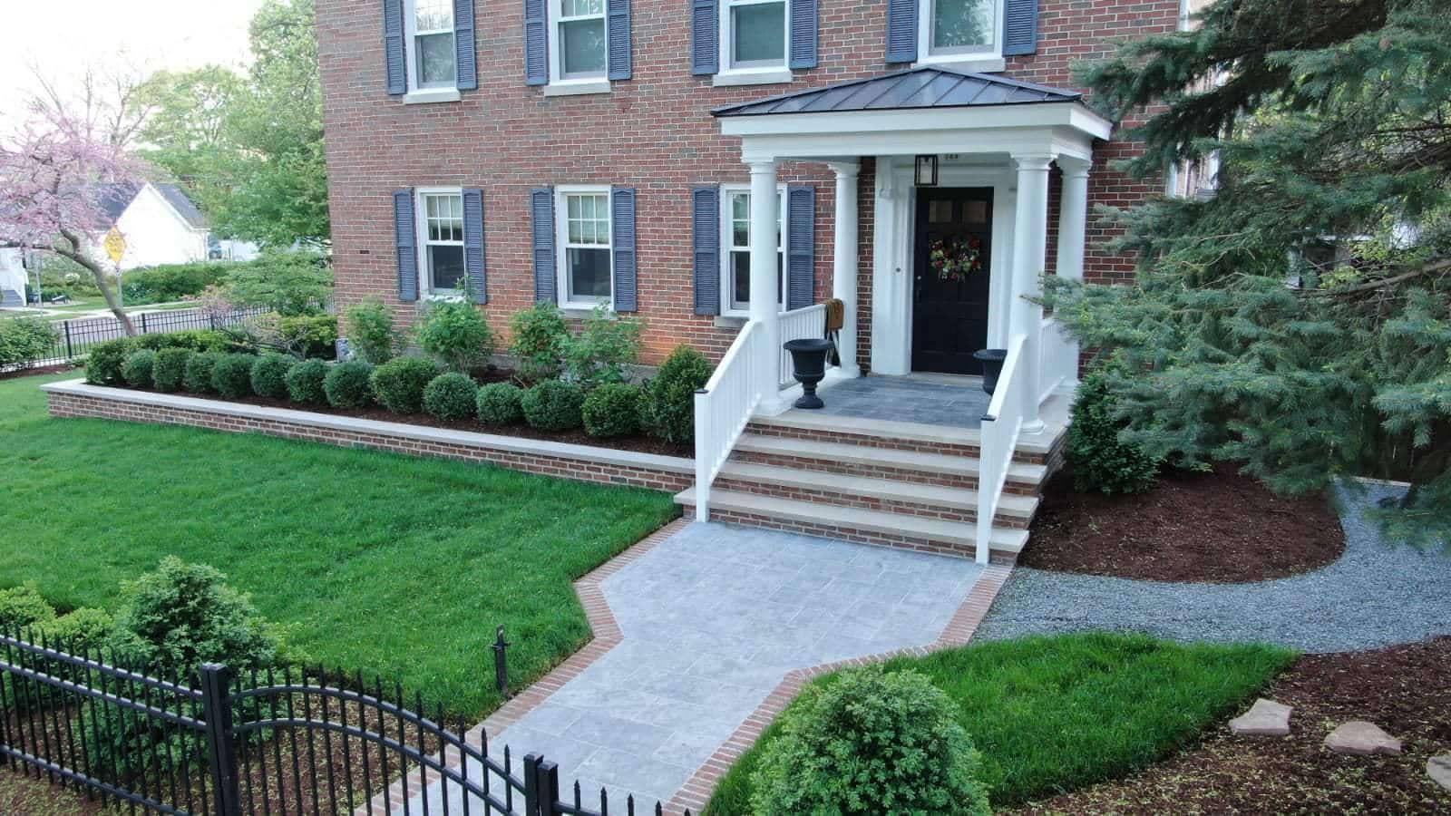 Brick house with a paved walkway, steps, and manicured landscaping.