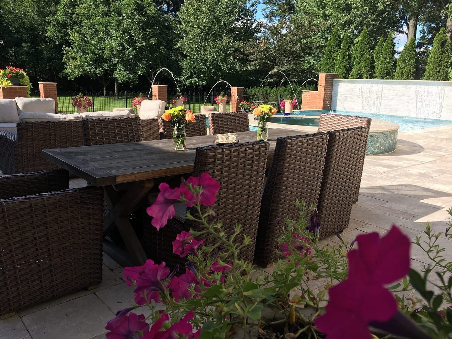 Outdoor patio with table and chairs, flowers, and a small fountain.