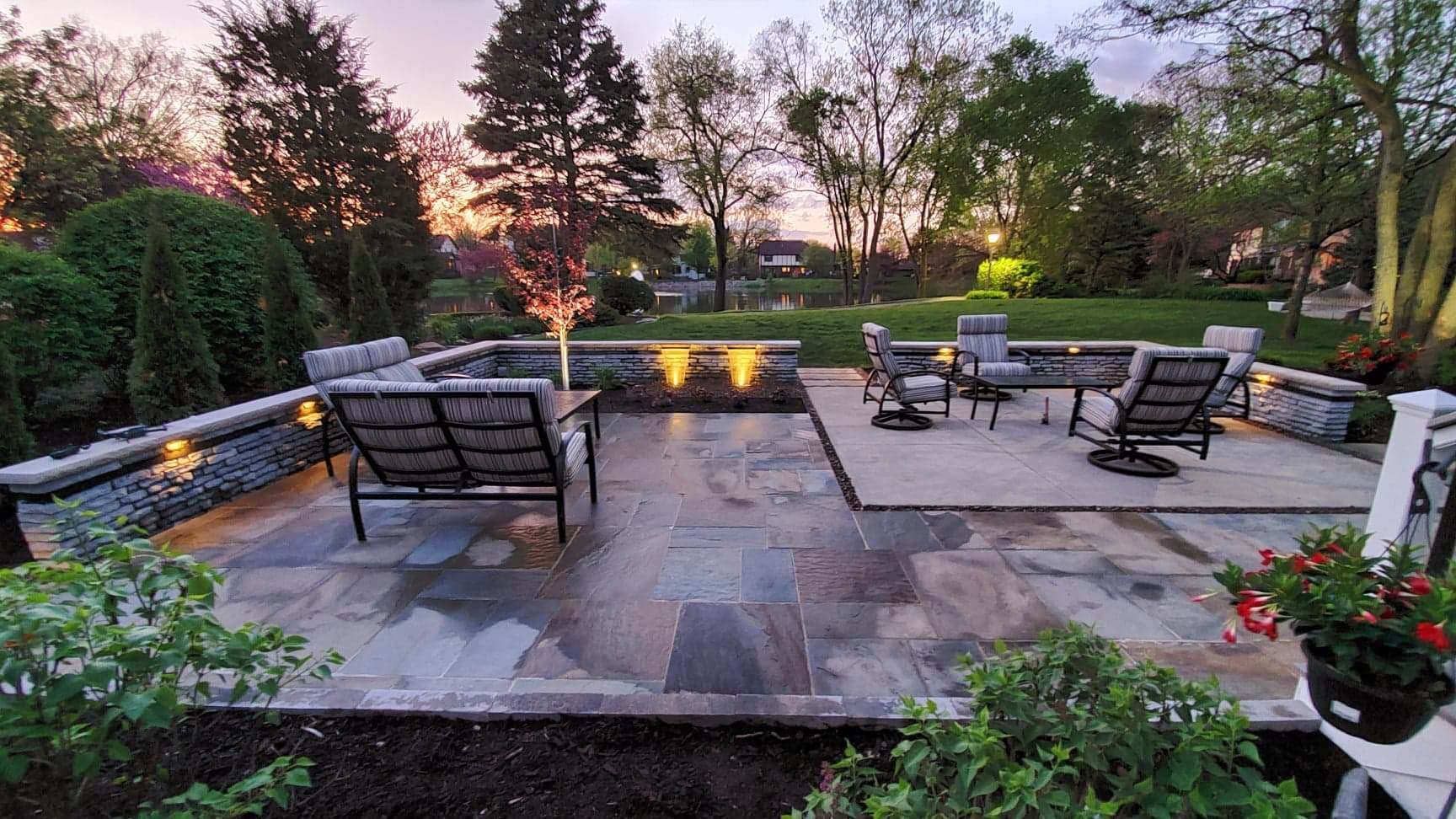 Patio with seating, stonework, and landscaping at dusk.