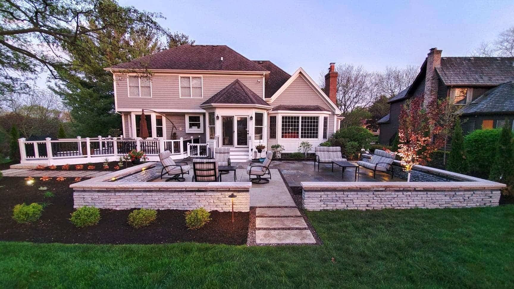 Backyard patio with a house, brick walls, landscaping, and outdoor furniture.