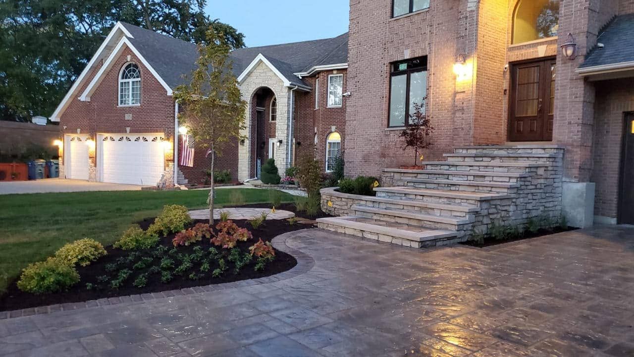 Brick house with stone steps, landscaped lawn, and paved driveway.