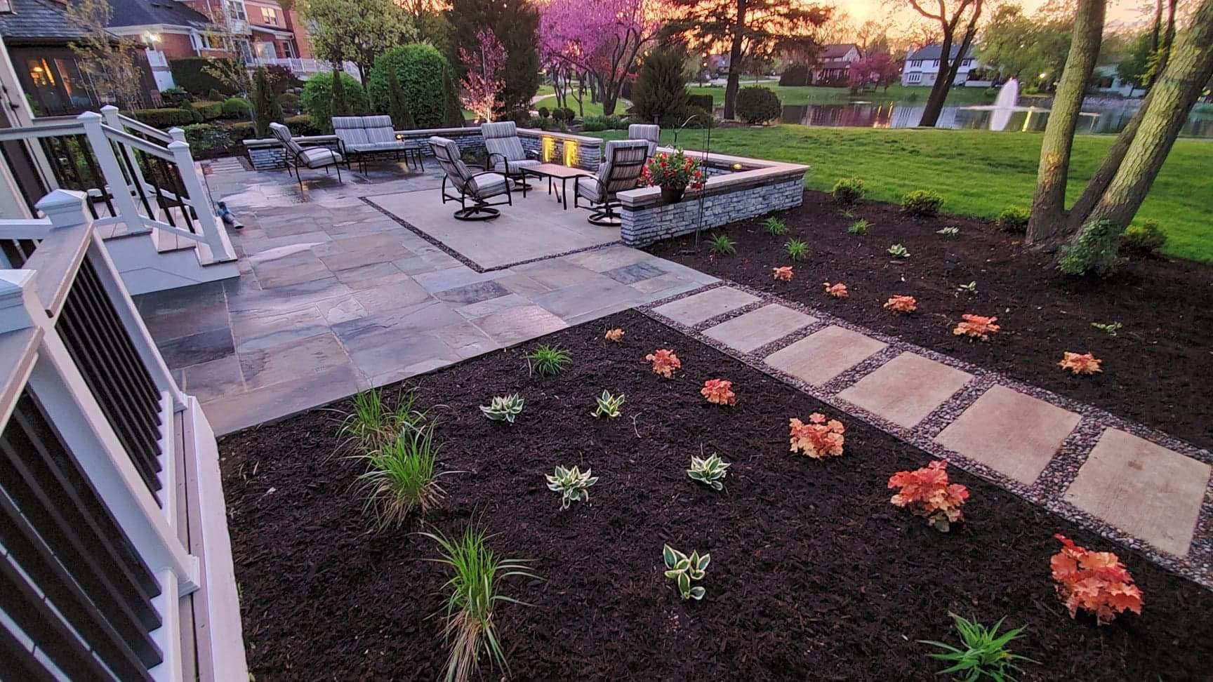 Patio overlooking a lake at dusk, with stepping stone path and landscaping.
