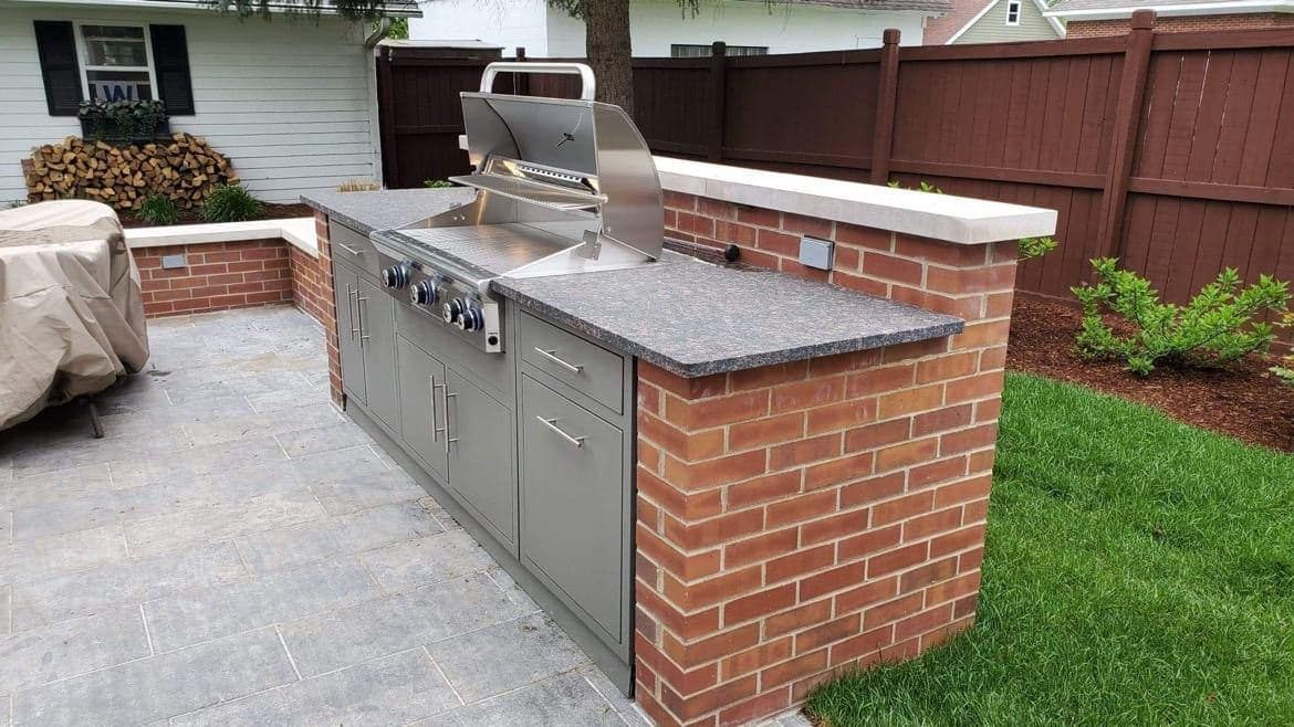 Outdoor kitchen with brick base, stainless steel grill, and granite countertop.