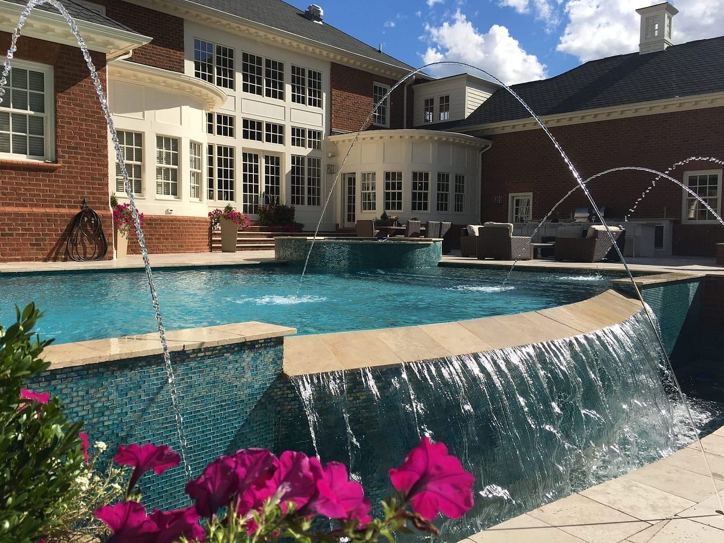Luxury home with a pool featuring waterfalls and fountains, with a red brick exterior.
