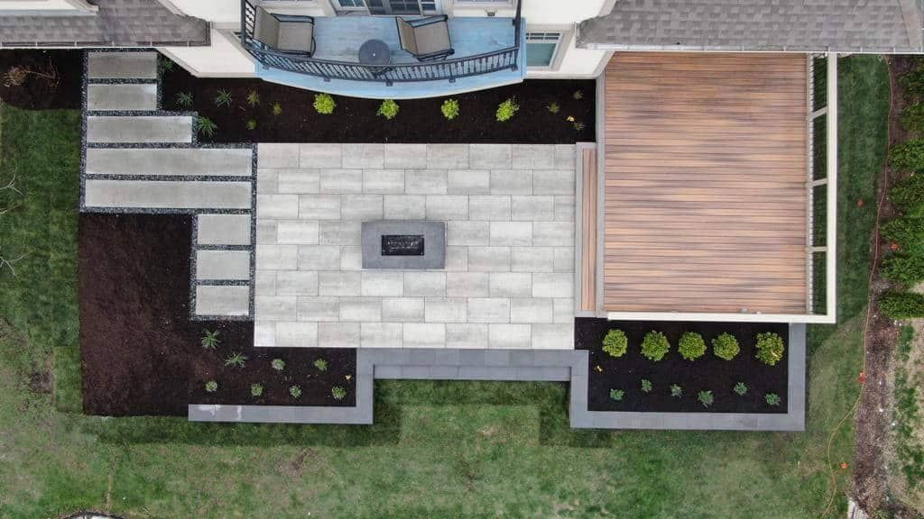 Overhead view of patio with fire pit, landscaping, deck, and stairs.