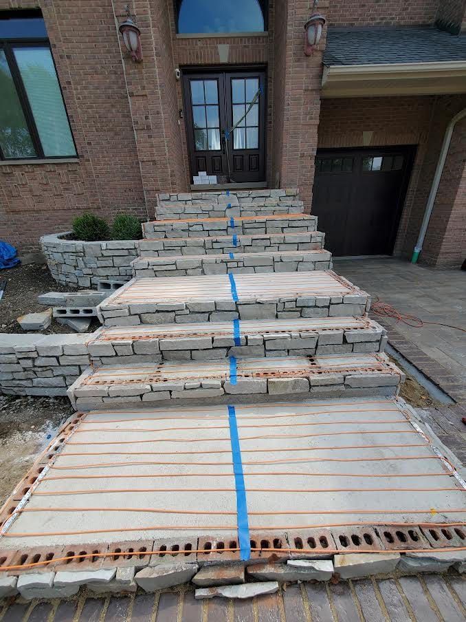 Stone steps leading to a home's front door, under construction with blue tape. Brick and stone elements.