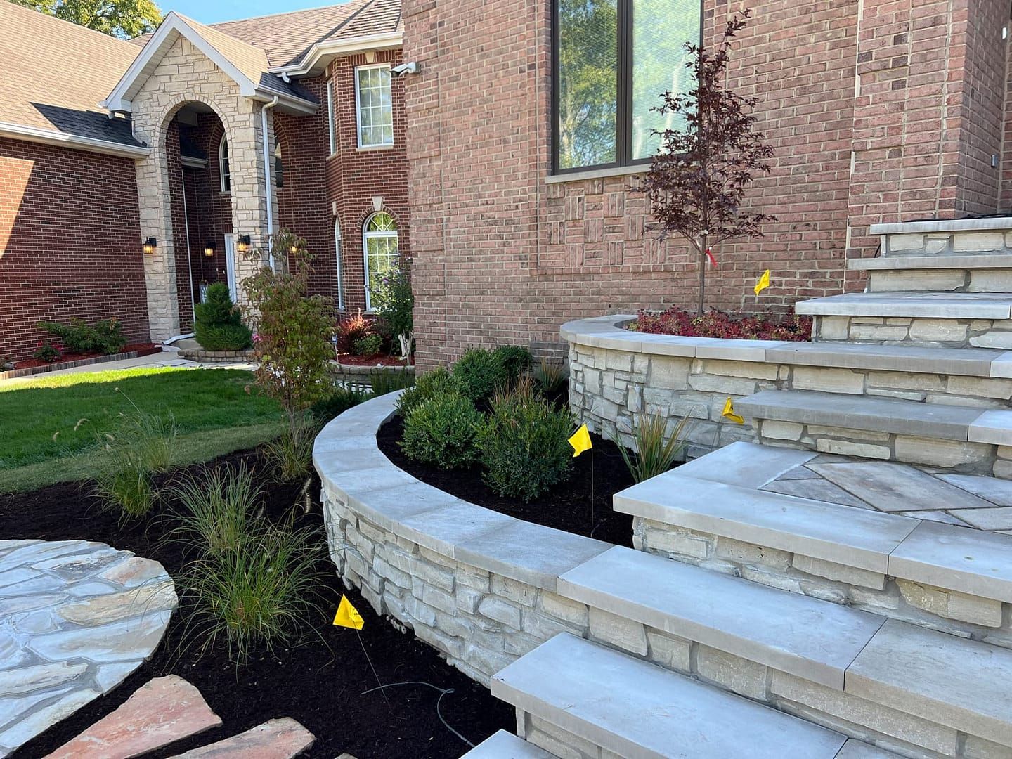 Brick house with stone steps, retaining wall, and landscaped garden.