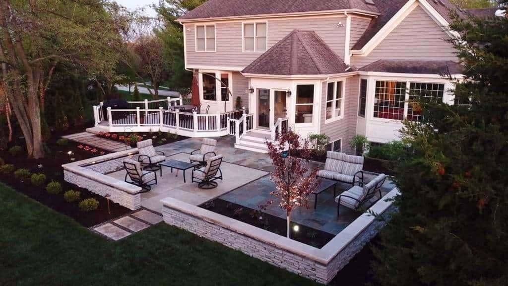 Backyard patio with seating and raised garden beds, connecting to a house with gray siding.
