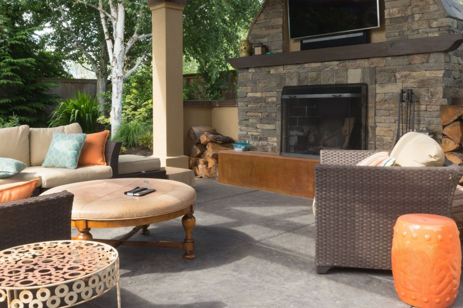 Outdoor patio with stone fireplace, couches, and round coffee table.