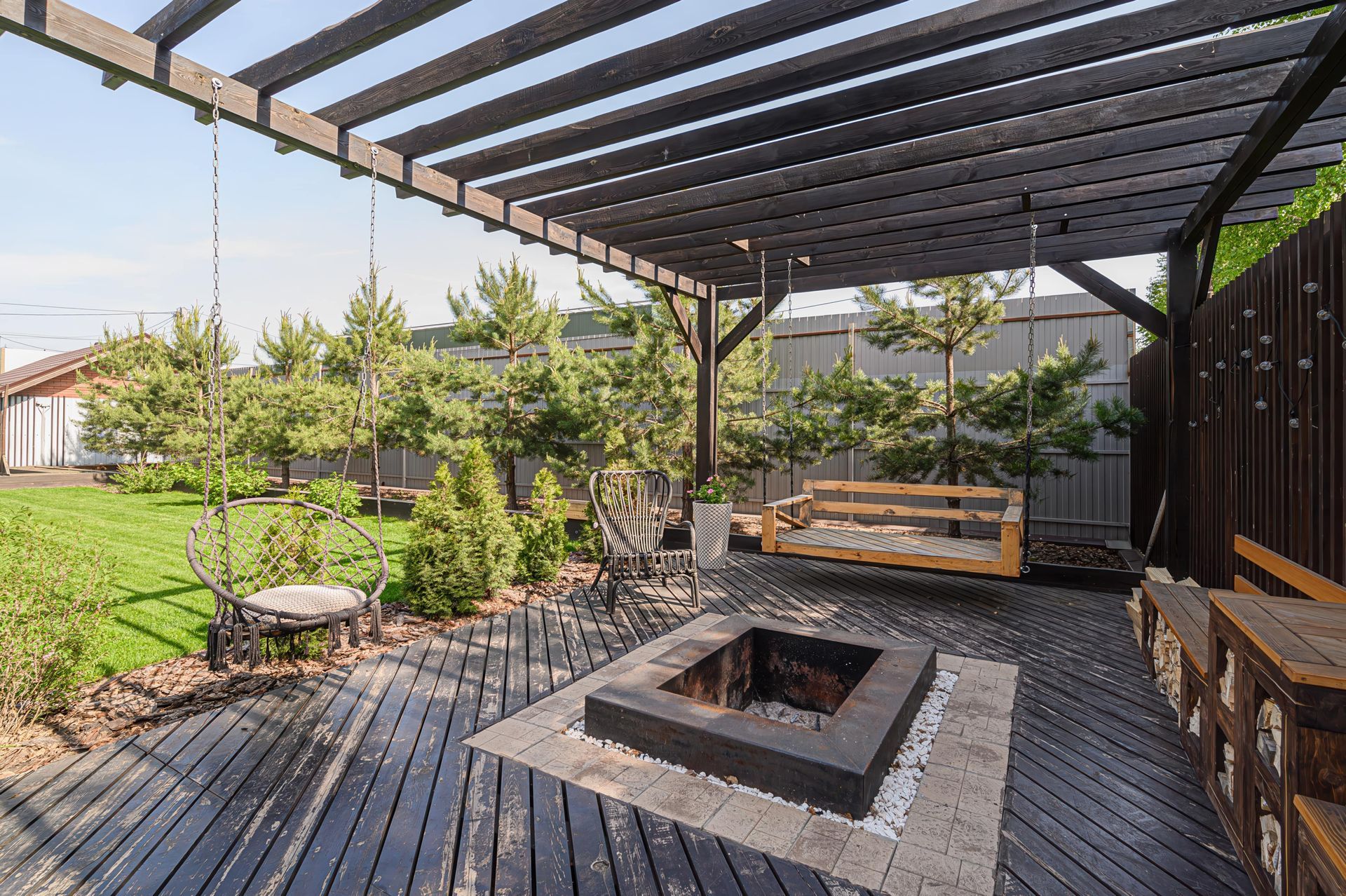 Backyard patio with a pergola, swings, fire pit, and wooden deck.