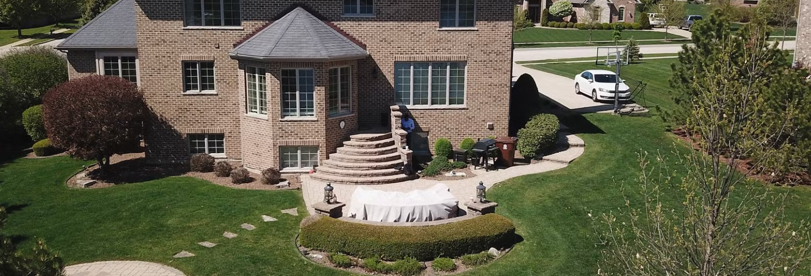 A brick house with a porch and a car parked in the driveway.