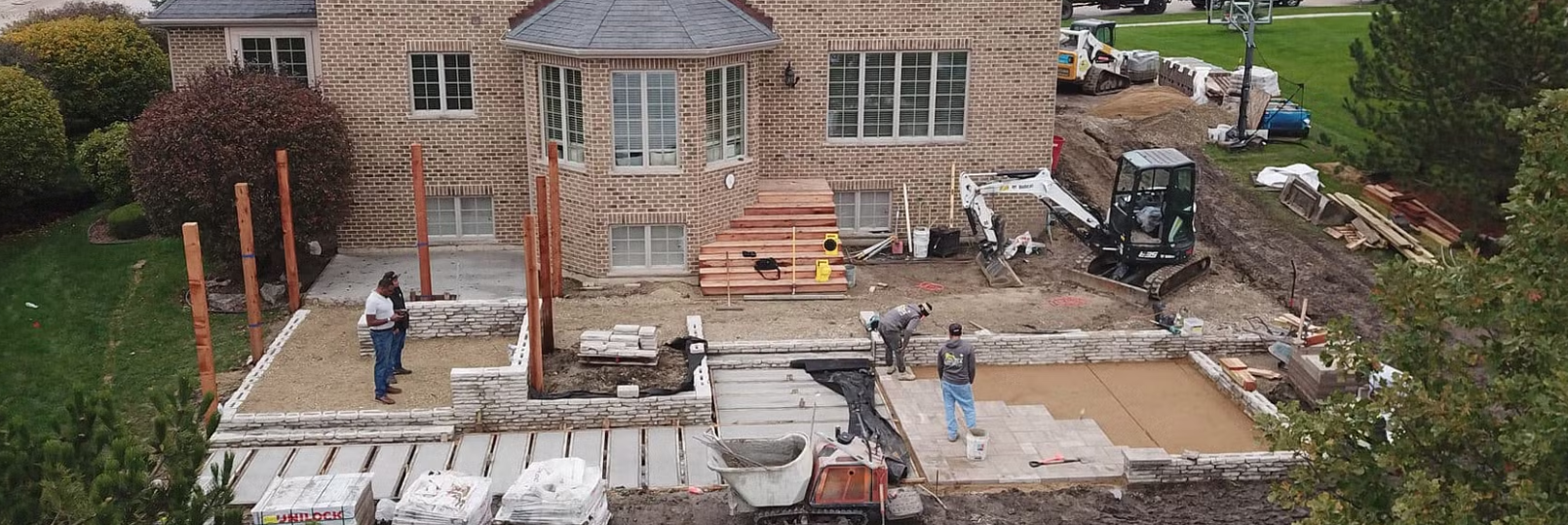 Construction site with a house, workers, and machinery.
