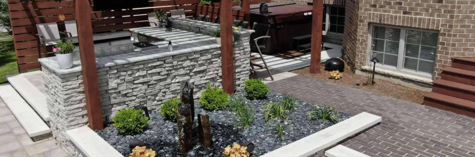 Outdoor patio with water feature and brick facade of a house.