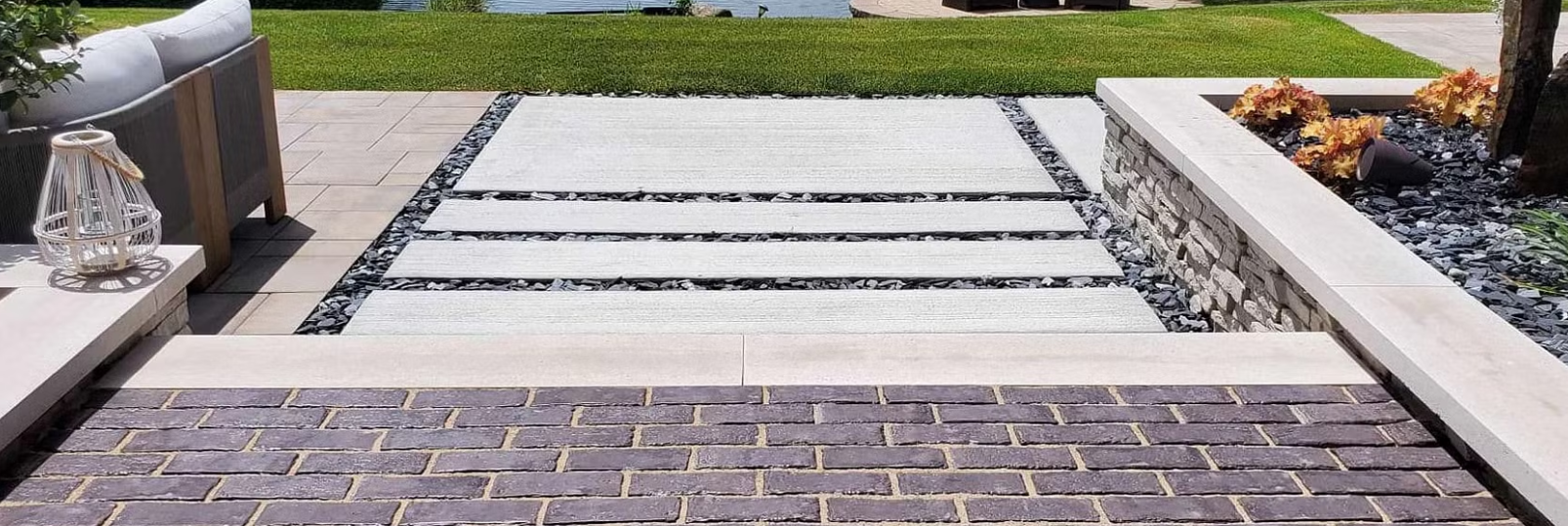 Stone steps with a brick landing and white pavers leading to a grassy area.