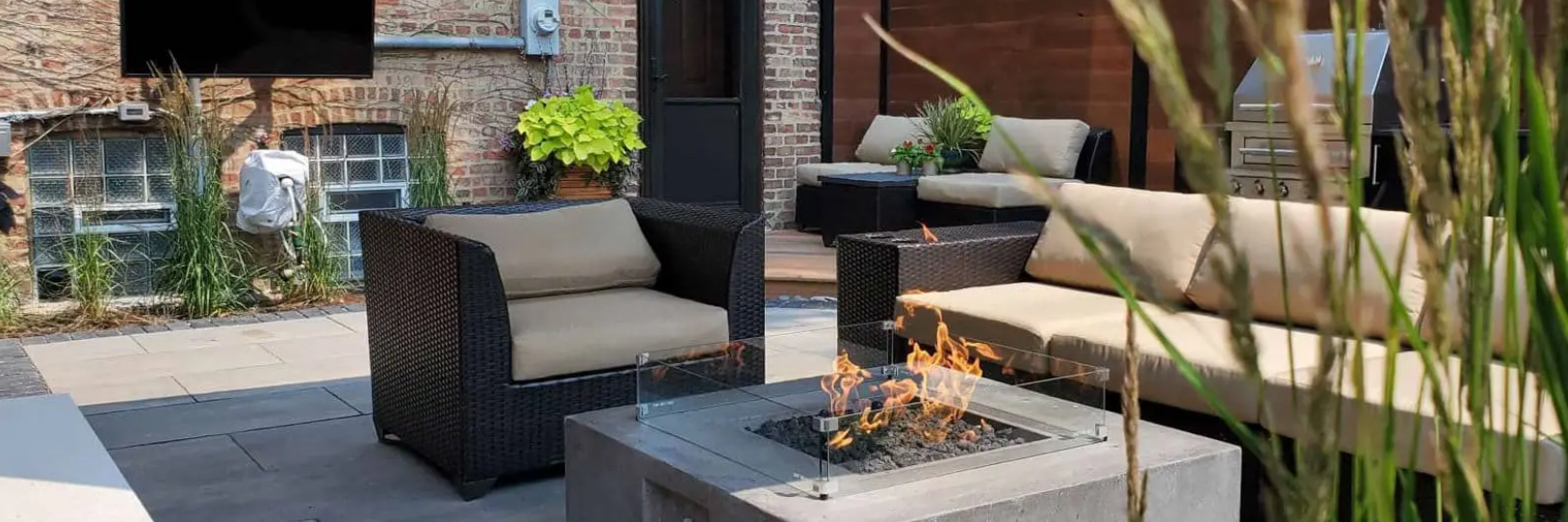 Outdoor patio with seating area, a fire pit, and greenery.