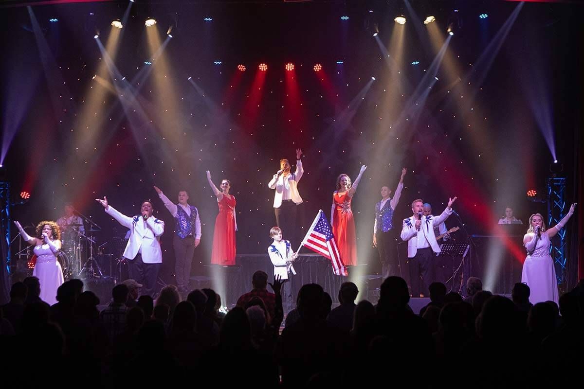 A Group of People standing on a Stage holding an American Flag - Pigeon Forge, TN - Mountain of Entertainment Theater 