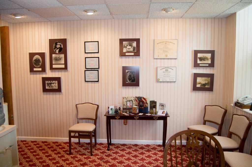 An interior shot of a room, possibly a waiting area, with chairs and framed artwork on the walls.