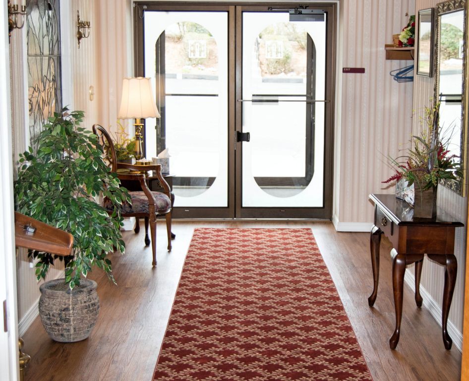 Entrance hall with red patterned runner, glass doors, and decorative furnishings.
