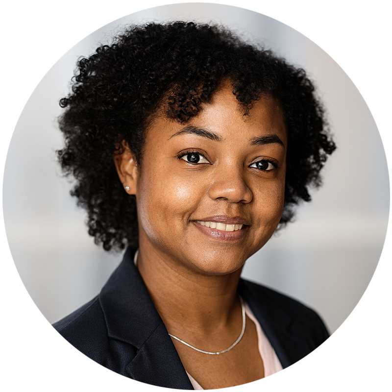 Smiling Black woman with curly hair, wearing a blazer and necklace.