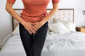 Woman holding lower abdomen, showing discomfort from urinary leakage.

