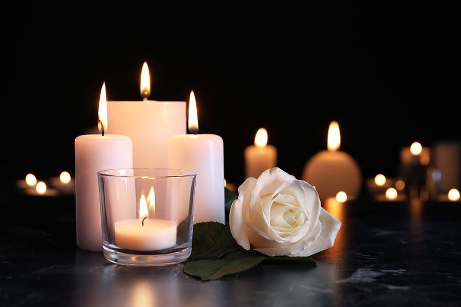 a white rose sits in front of lit candles
