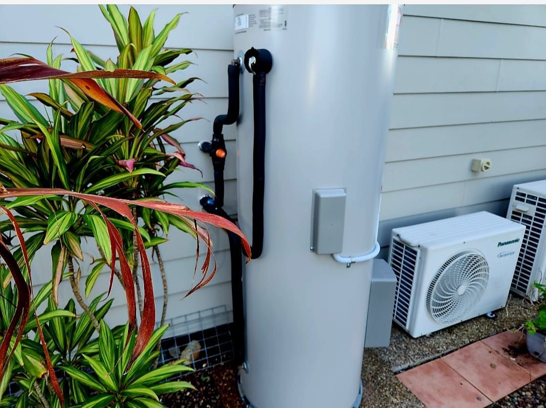 Person in red gloves inspects boiler with handheld device. Pipes and wires are visible.
