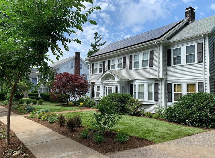 A white house with black shutters and solar panels on the roof.