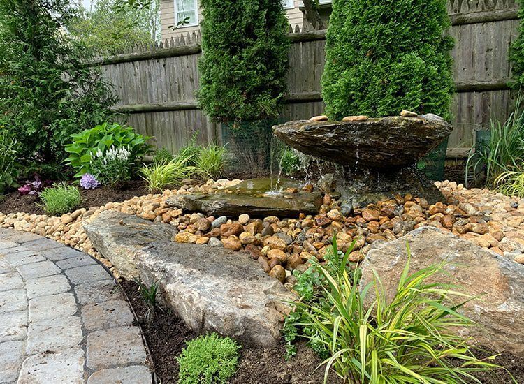 There is a fountain in the middle of the garden surrounded by rocks.