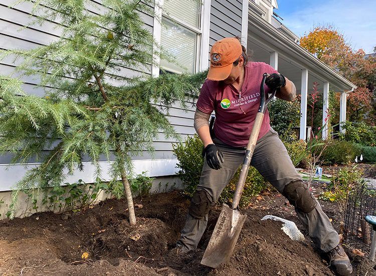A man is digging in the dirt with a shovel in front of a house.