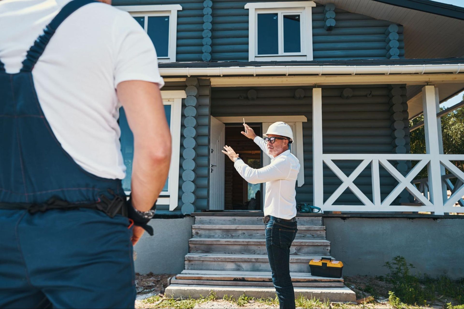 Home inspector discussing details with a worker outside a house under inspection.