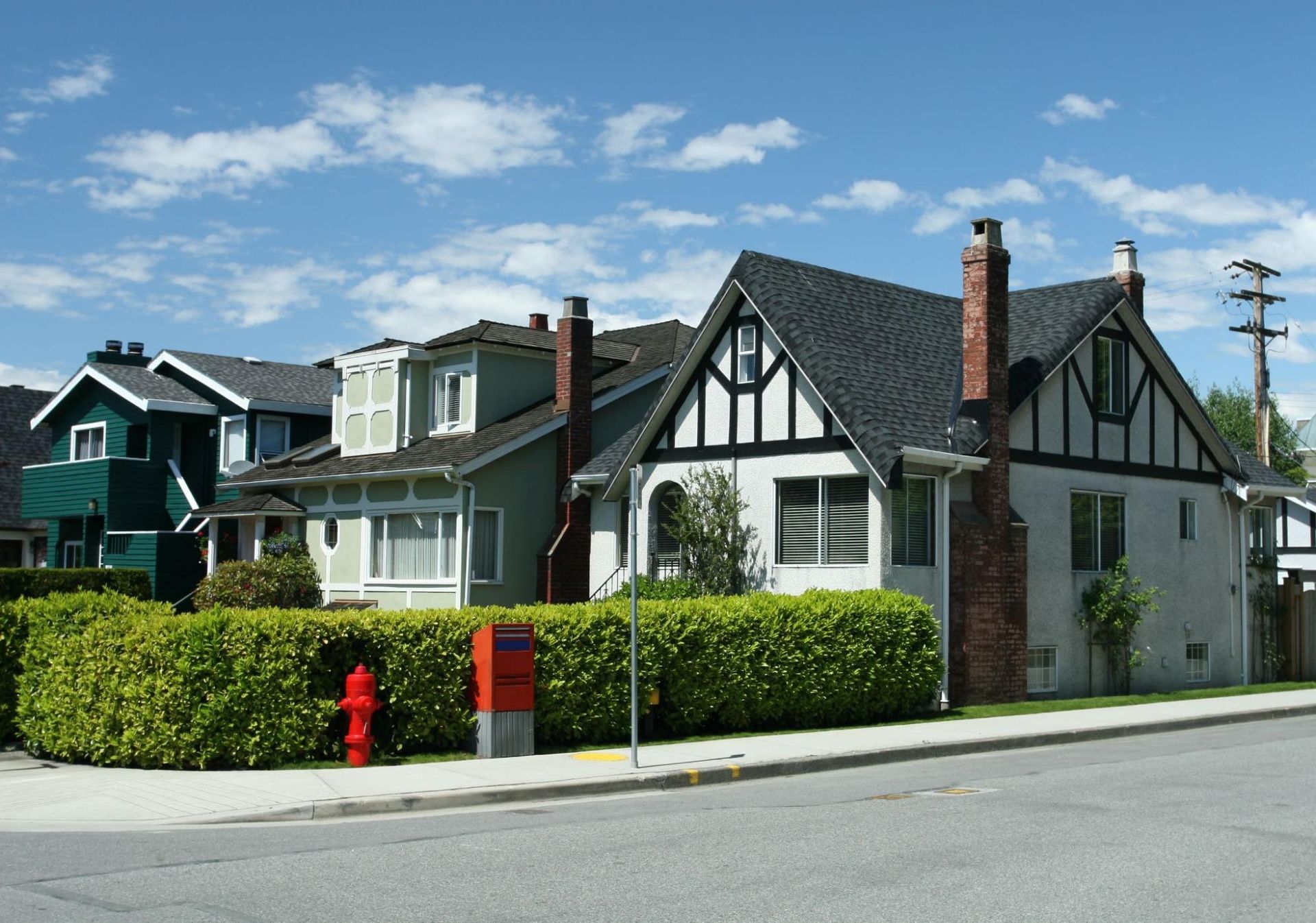 Quiet residential street with well kept single family homes, mature landscaping, sidewalks, and clear views of roofs, chimneys, and exterior siding in a suburban neighborhood.
