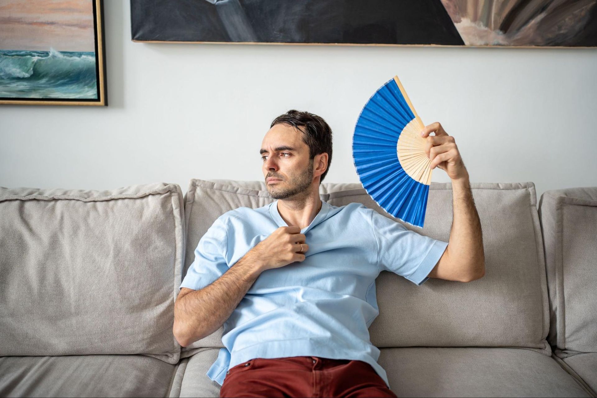 man fanning himself inside a hot house