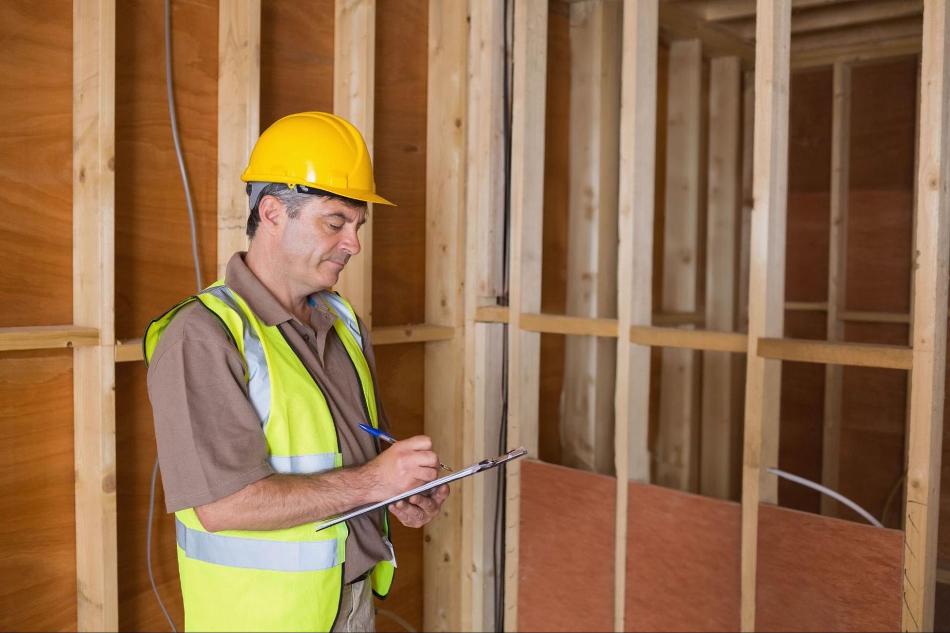 Home inspection Huntsville professional inspecting interior framing and taking notes during a reside
