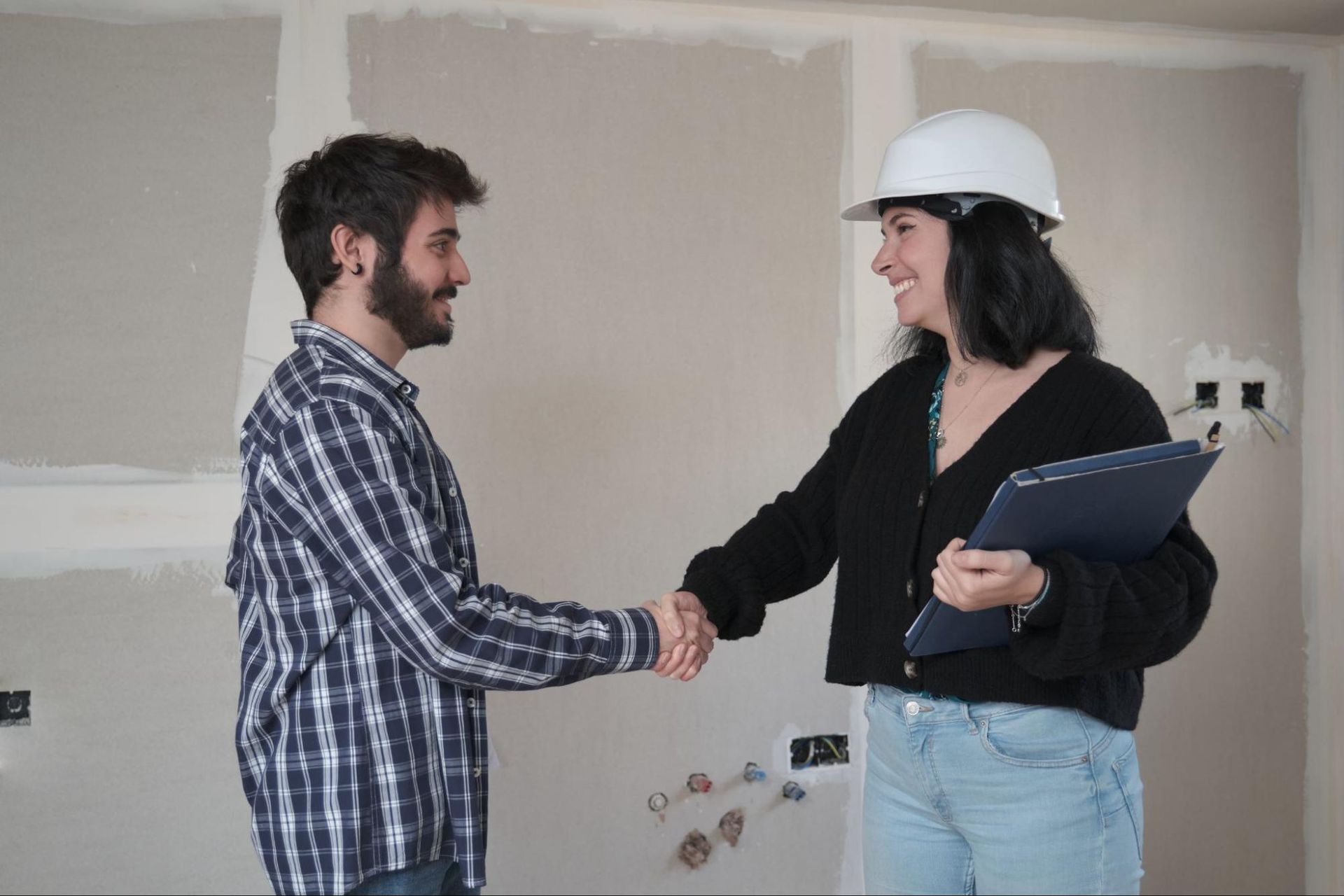 Home inspection with a homeowner and inspector shaking hands in an unfinished house.