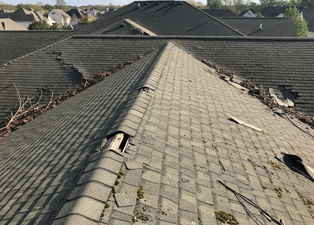 Rooftop view of shingles showing visible wear and storm damage