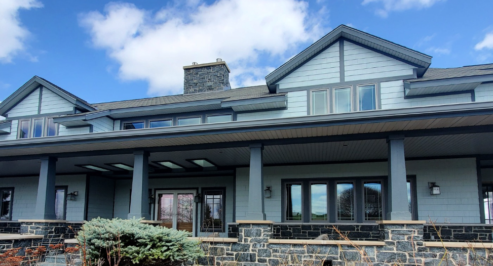 A large house with a large porch and a blue sky in the background.