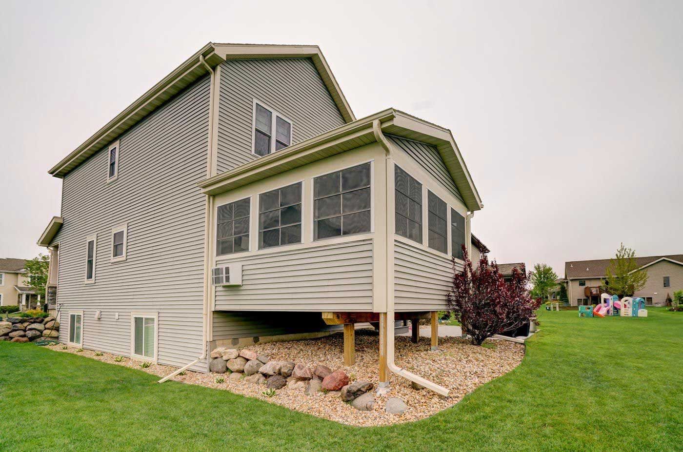 A large house with a screened in porch on the side of it.