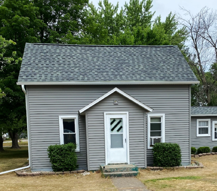 A small gray house with a white door and windows